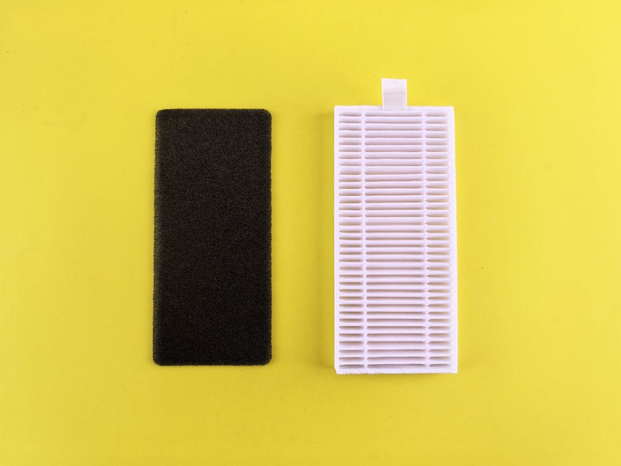 Black foam filter and white air filter on bright yellow backdrop showcasing air purification essentials.