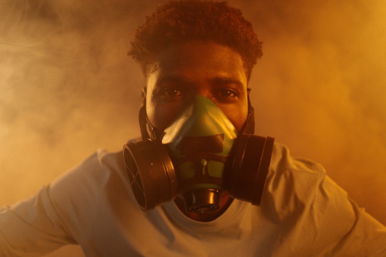 Close-up of a man wearing a respirator surrounded by smoke, highlighting air pollution and protection.